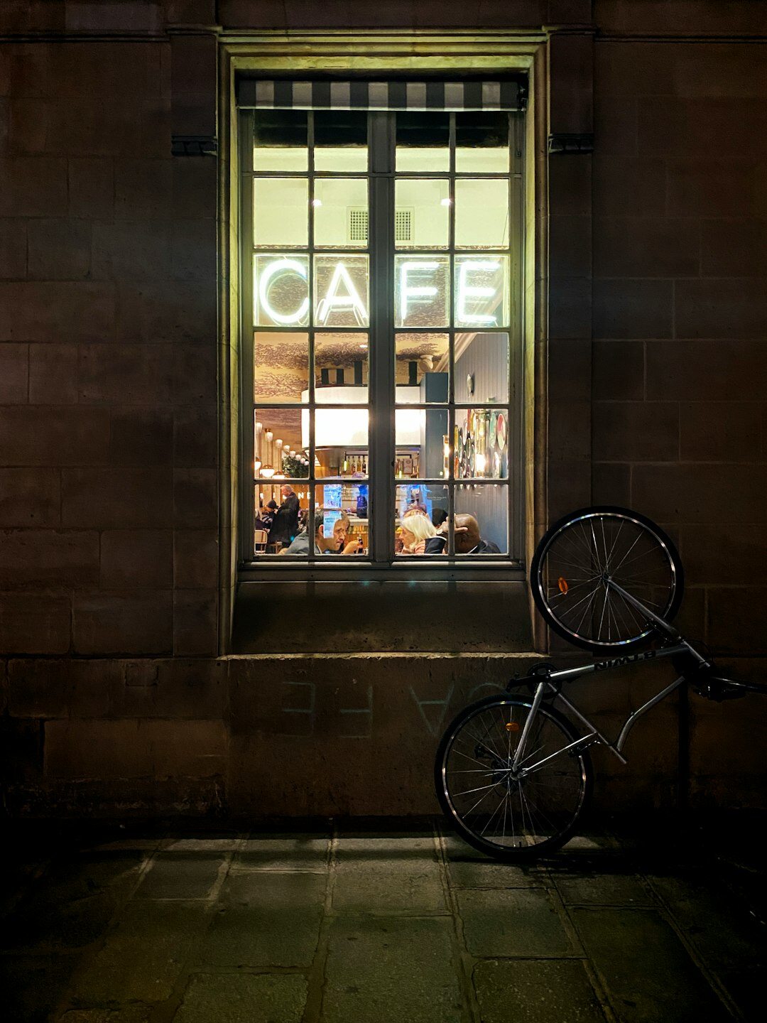 Book cover illustration of a lit café window at midnight for a detective novel titled Café de Medianoche
